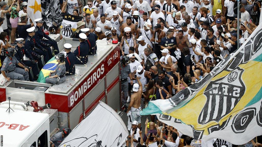 Pele's coffin is escorted on a fire truck through Santos where fans are lining the streets