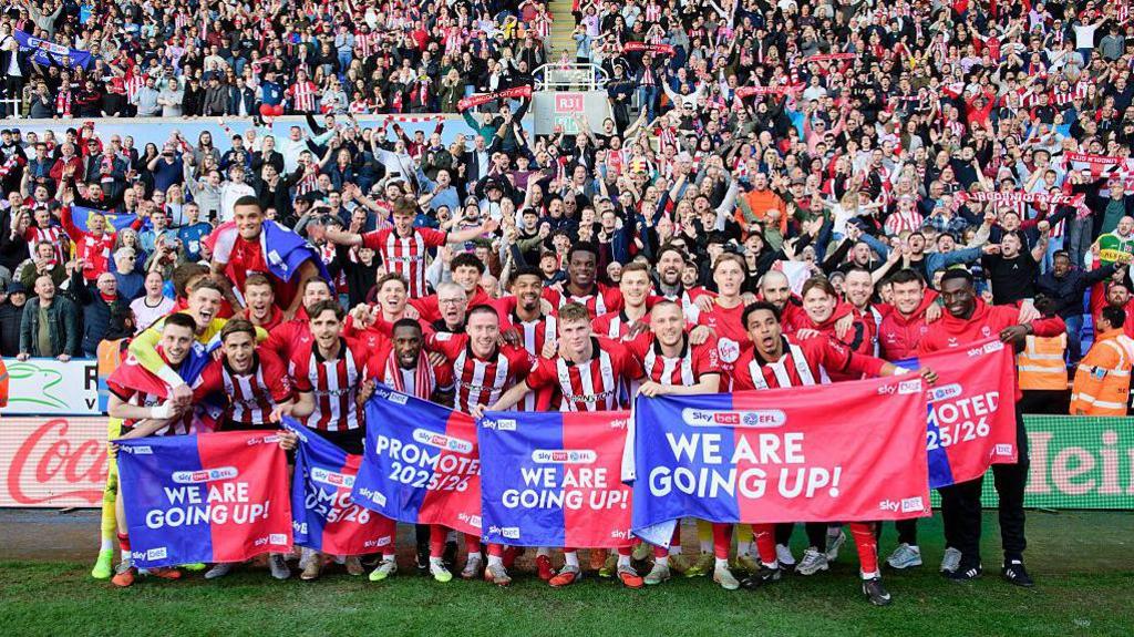 The Lincoln City squad celebrating their promotion infront of their visiting supporters at Reading's Select Car Leasing Stadium.