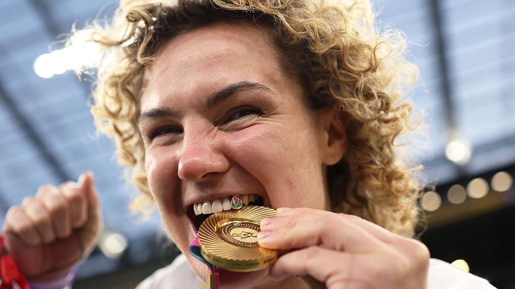 Ellie Kildunne biting her gold medal. 