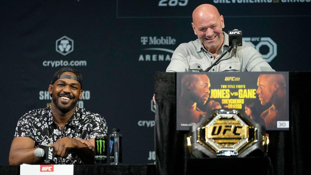 Jon Jones sits beside Dana White at a news conference, both laughing