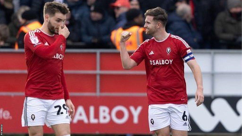 Salford City's Luke Garbutt celebrates with goal scorer Elliot Watt