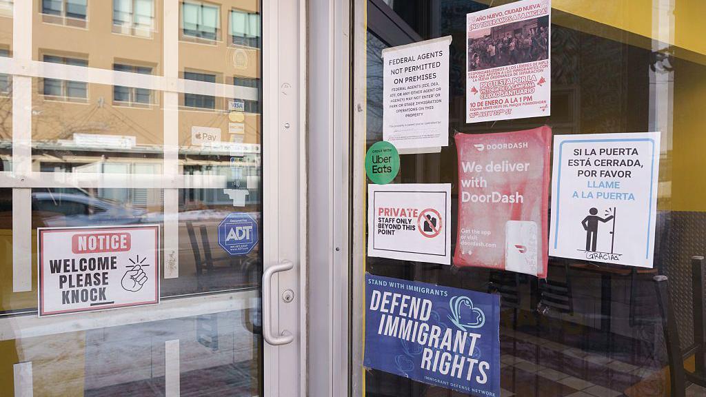 a bunch of signs on a storefront advocating for immigrants and saying no ICE allowed