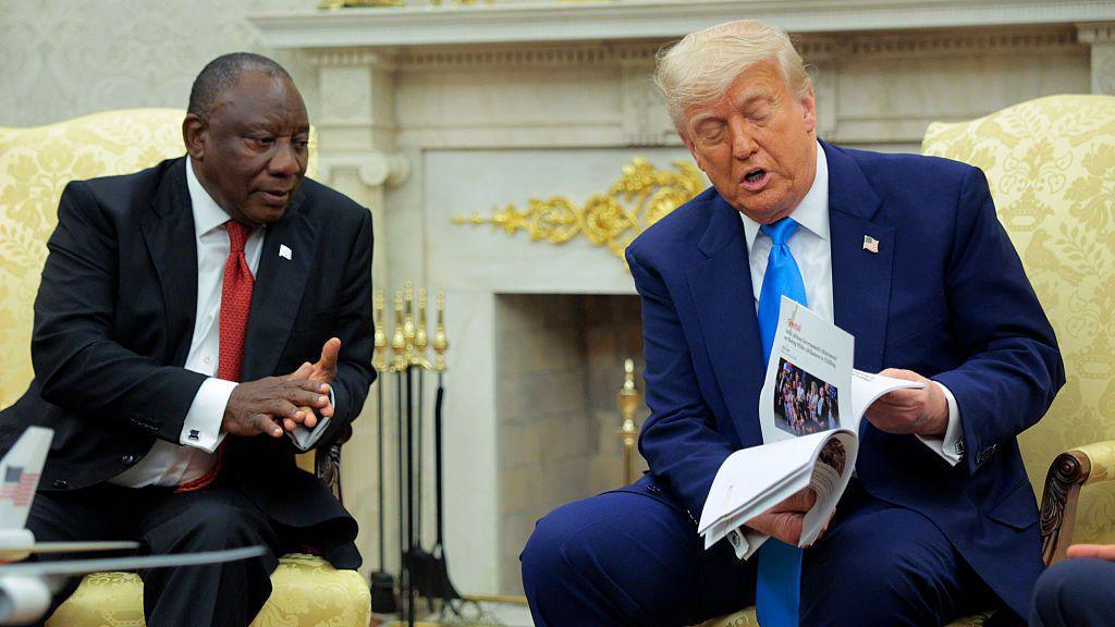 President Donald Trump show President Cyril Ramaphosa a pile of documents