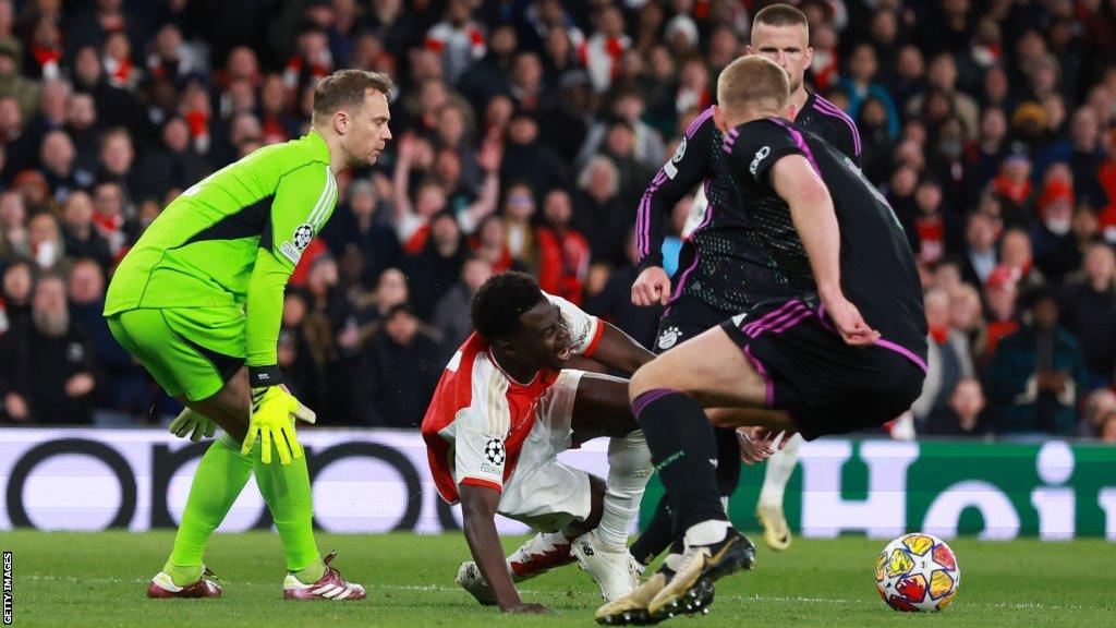 Bukayo Saka goes down after colliding with Manuel Neuer