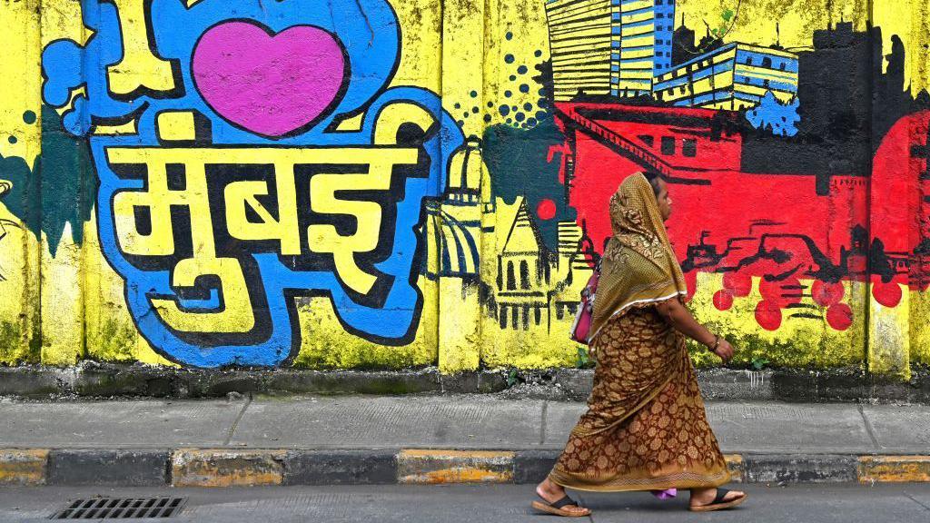 A woman walks past a wall mural reading 'I love Mumbai' along a street in Mumbai on August 31, 2023. (Photo by Indranil MUKHERJEE / AFP) (Photo by INDRANIL MUKHERJEE/AFP via Getty Images)