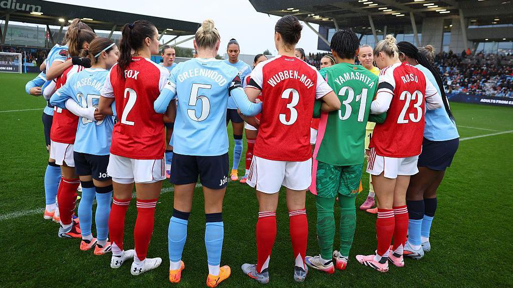 Manchester City players and Arsenal players huddle together