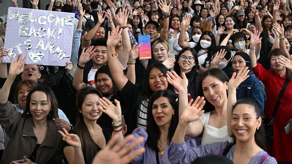 This photo taken on June 13, 2025 shows fans of K-pop boy band BTS posing for photos as they queue up for the annual 'BTS Festa' celebrating the group's debut anniversary