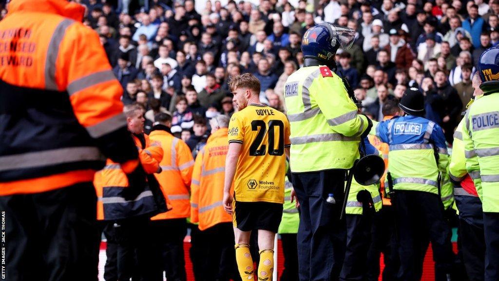 Tommy Doyle walks amongst police and stewards