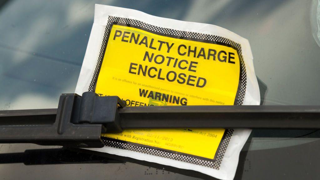 Yellow parking ticket on car windscreen