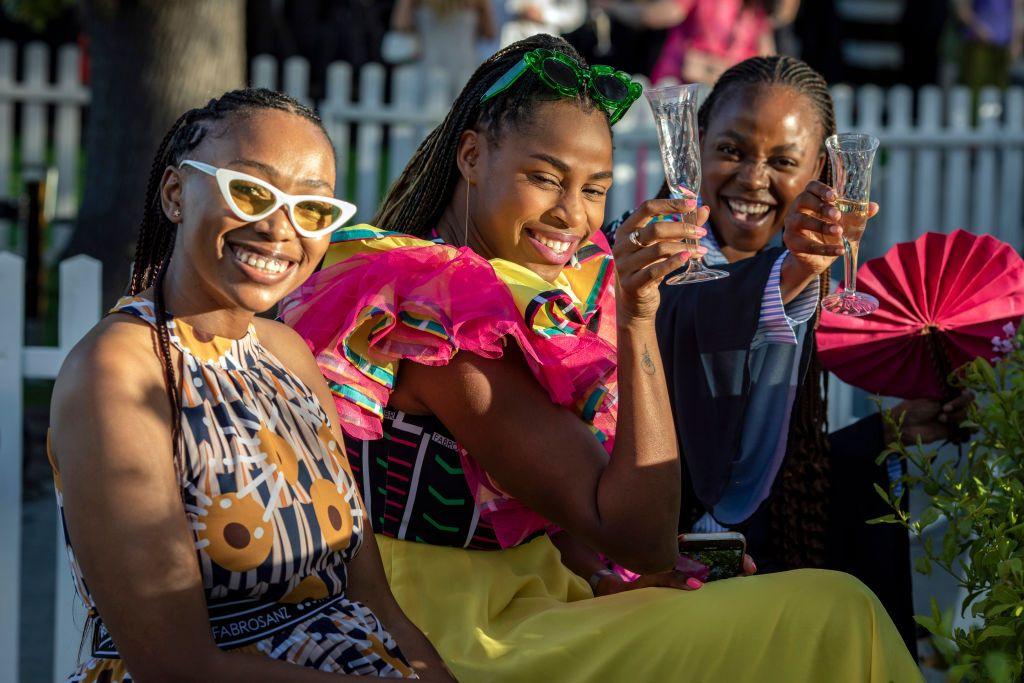 Three women smile, two of them are raising champagne flutes.