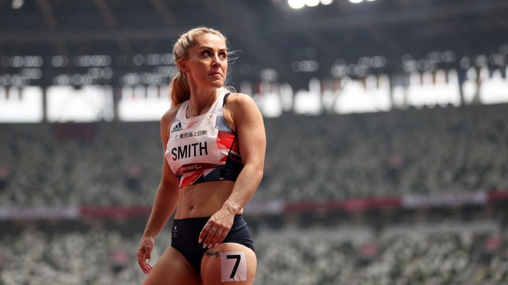 Ali Smith stood with a large crowd around her inside a big athletics stadium. 