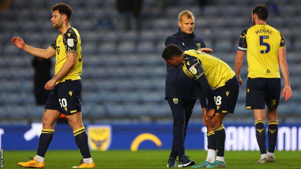 Oxford United boss Liam Manning speaks to his players on the field