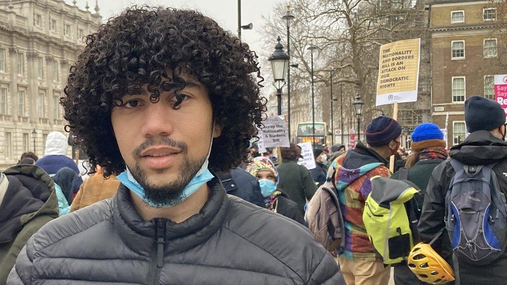 Leo Power stands in front of protestors at Downing Street who are demonstrating against the Nationality and Borders Bill