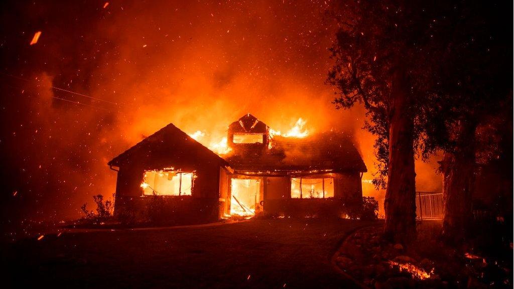 Embers fly through the air as a home burns during the Hillside Fire in the North Park district of San Bernardino, California, on 31 October