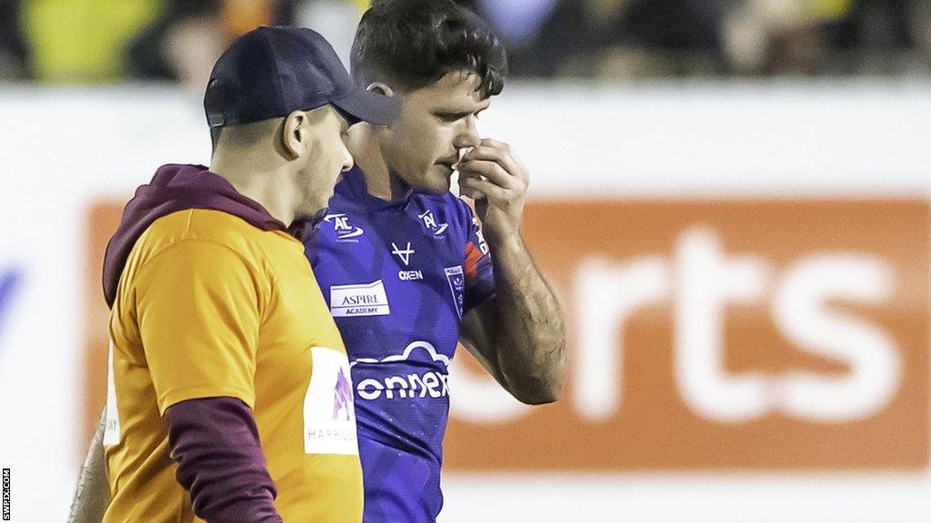 Lachlan Coote is led off the field by the Hull KR medical staff after suffering a head injury