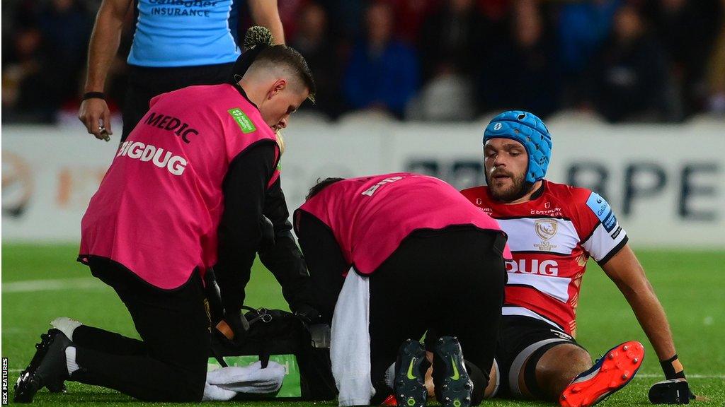 Zach Mercer (right) is treated on the pitch by two medics