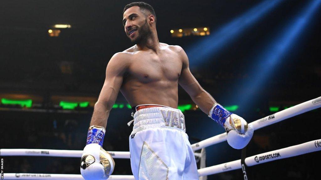 Galal Yafai smiles in the ring dressed in white gloves and shorts