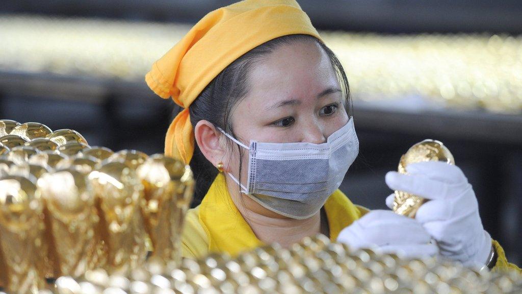 A worker checks a replica of the World Cup trophy at a plant of a craft factory in Dongguan, China.