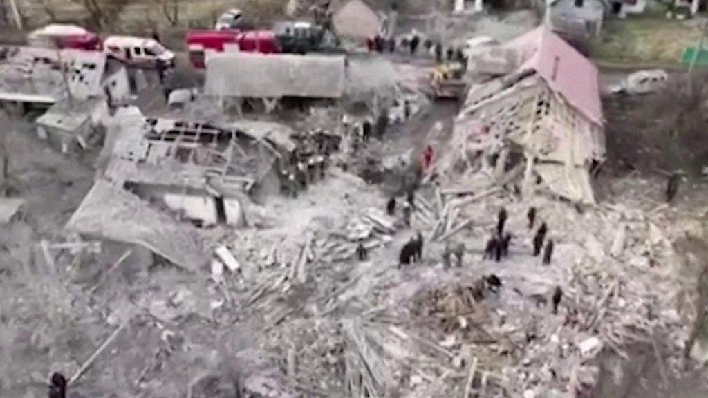 Destroyed building with people standing in rubble