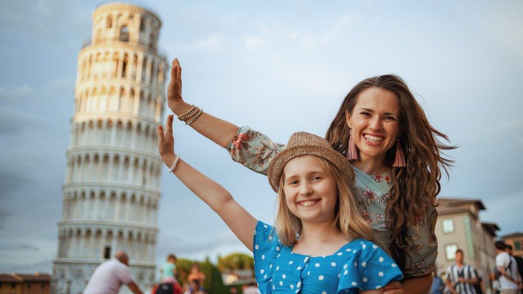 A woman and child pose with the Tower of Pisa