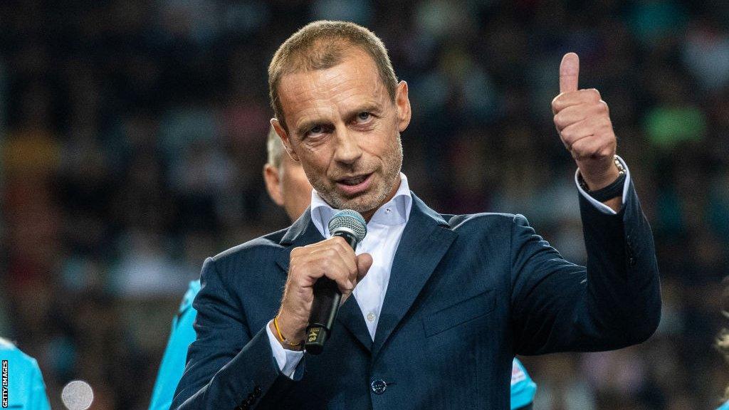 Aleksander Ceferin speaking into a microphone and giving a thumbs-up gesture