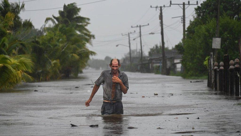 A resident of the coastal town of Guanimar, southwest of Havana, Cuba, wades through a flooded street after the passage of Hurricane Helene on 25 September, 2024