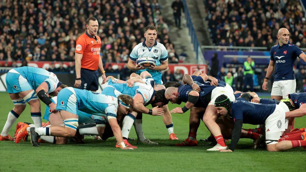 the french and scottish rugby teams during a scrum, scotland in a light blue kit and france in a dark blue kit