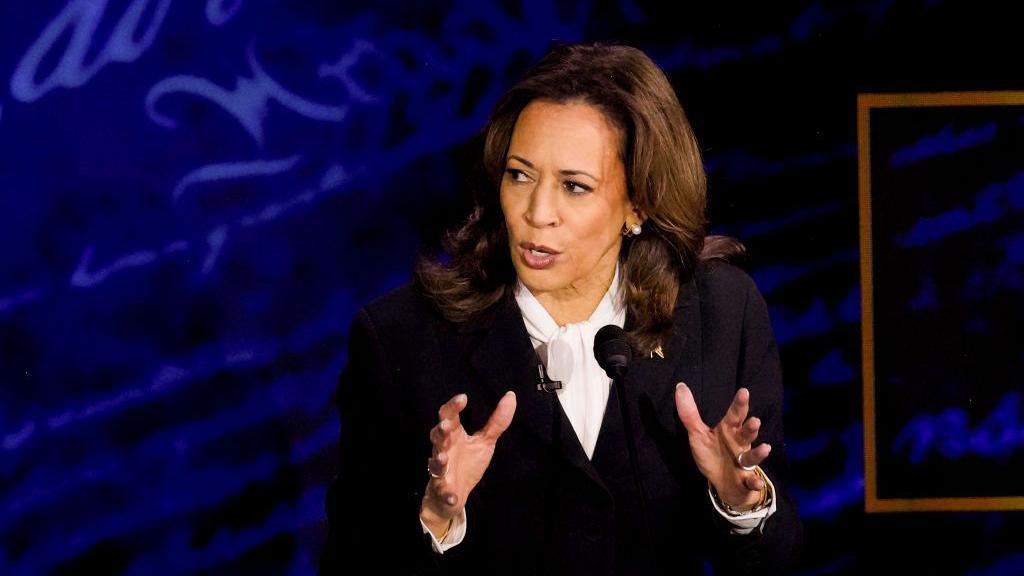 Presidential candidate Kamala Harris holds her hands in front of her, explaining a point in a TV debate