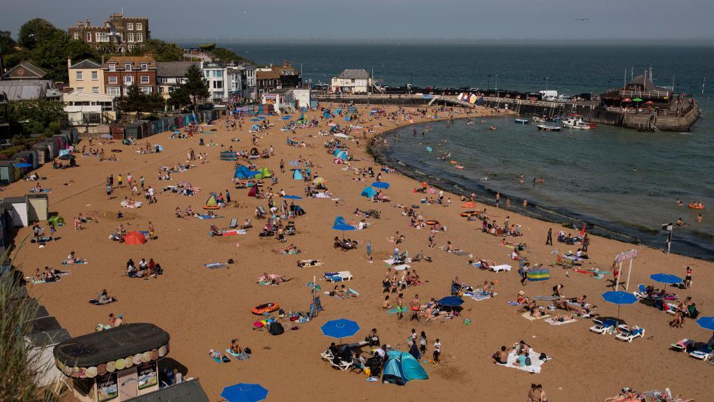 Viking Bay, a semi-circular bay with sunbathers lying under umbrellas