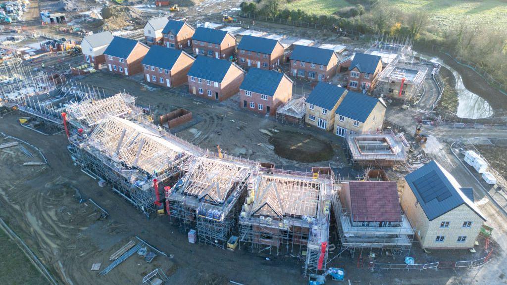 An aerial view of new houses being constructed on what was previously agricultural land.