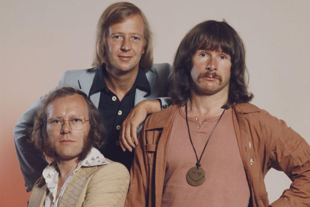 The Goodies: (l to r) Graeme Garden, Tim Brooke-Taylor and Bill Oddie in 1975. Oddie has a prominent medallion around his neck. They are all staring rather blankly into the camera.