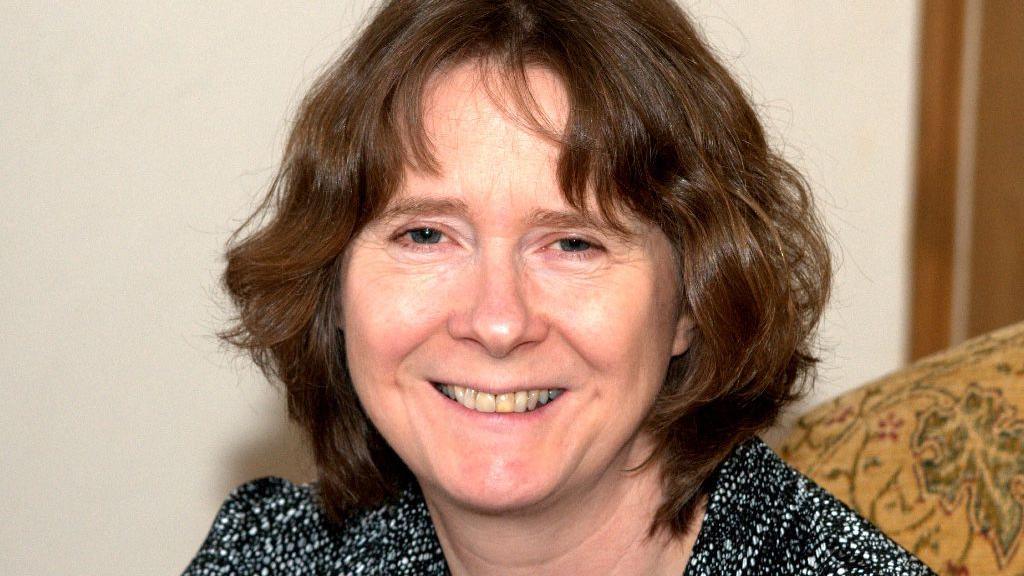 Atha Murphy is seen from her shoulders up. She is smiling and has shoulder-length, brown hair. 