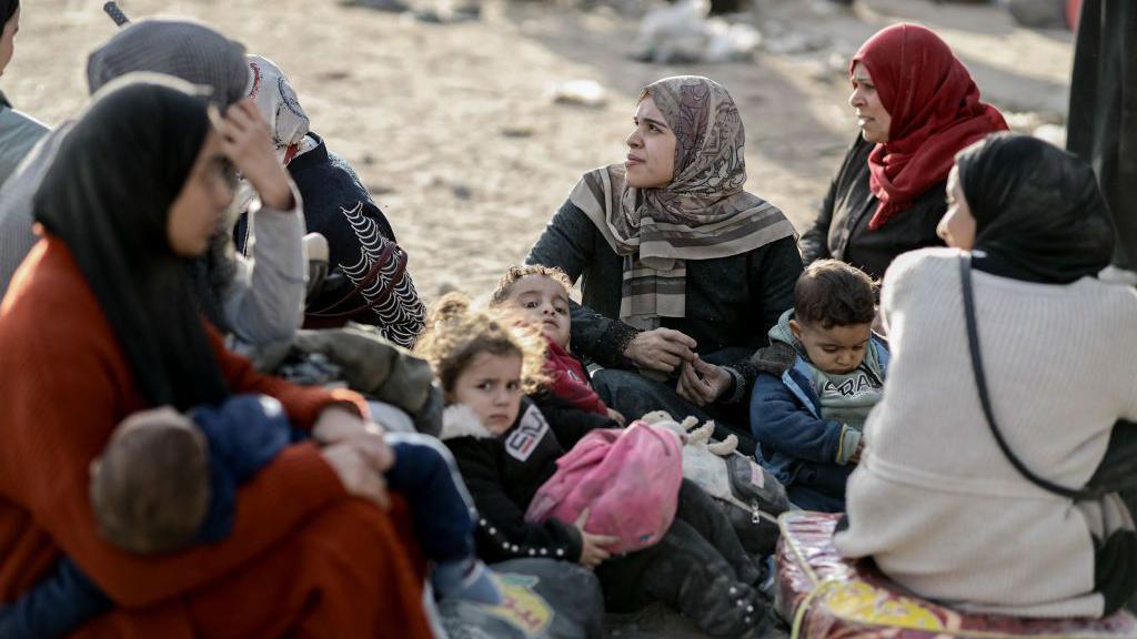 Displaced Palestinians fleeing Beit Lahia in the northern Gaza Strip, rest on Salah al-Din street (17 November 2024)