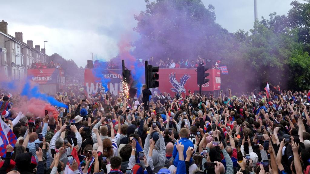 A huge crowd of Crystal Palace fans wave and take photos as the team's victory bus goes past them