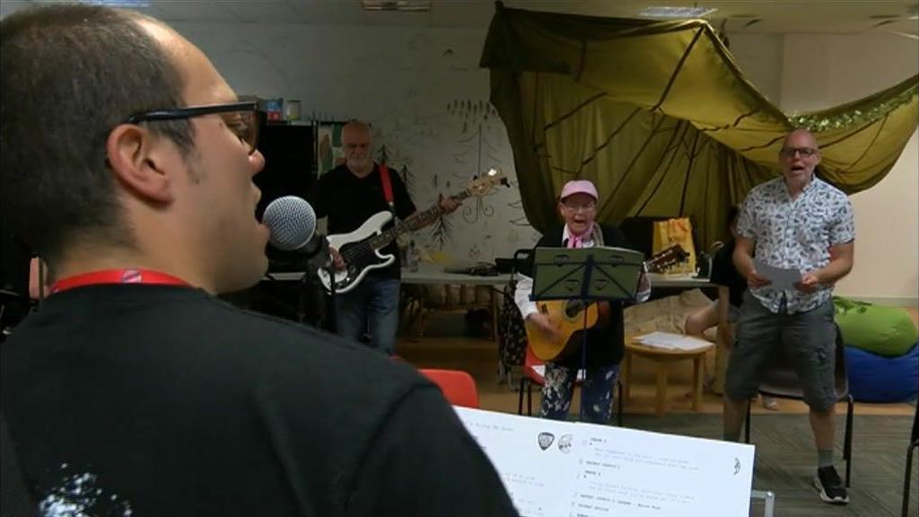 A group of people singing and playing the guitar