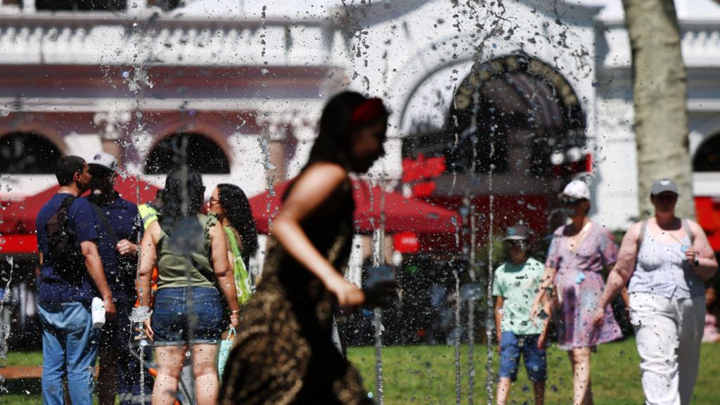 A person runs through water fountains to cool off 