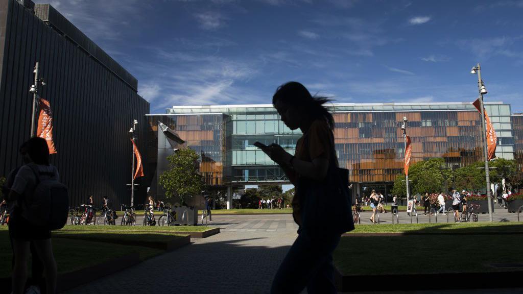 A silhouette of a woman walking on an Australian university campus