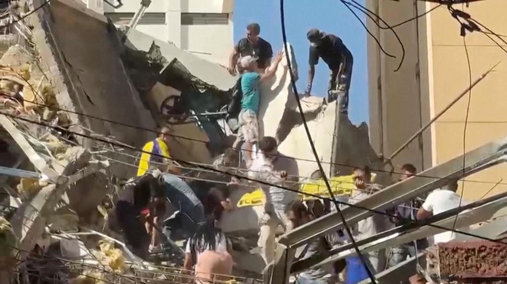 Rescue workers and residents stand atop a collapsed building in the aftermath of an earthquake in Cali, Colombia, August 10