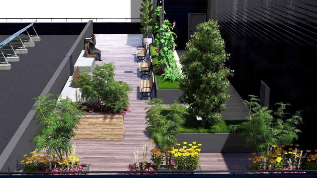 The rooftop terrace has a light beige patio flooring, with lots of benches to provide seating. There is also a lot of greenery on the terrace, with various types of plants and flowers.