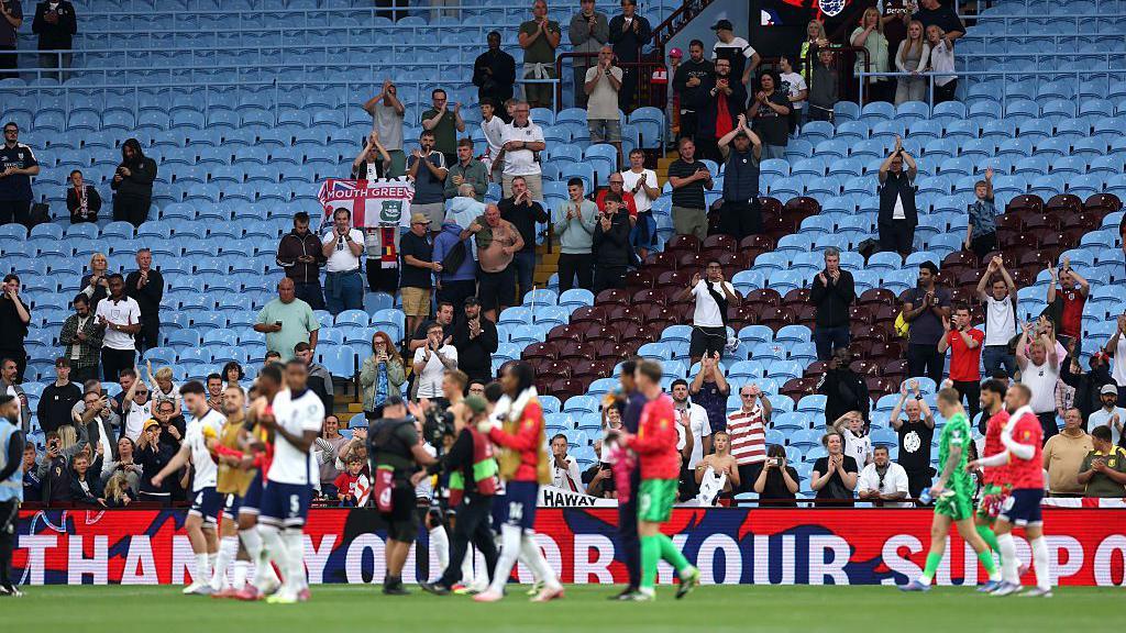 England players show their support to the remaining fans inside Villa Park