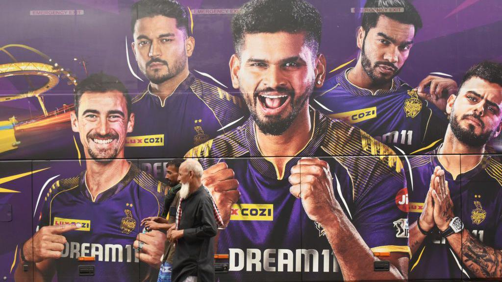 People are passing next to the Kolkata Knight Riders team bus in Kolkata, India, on May 26, 2024. 