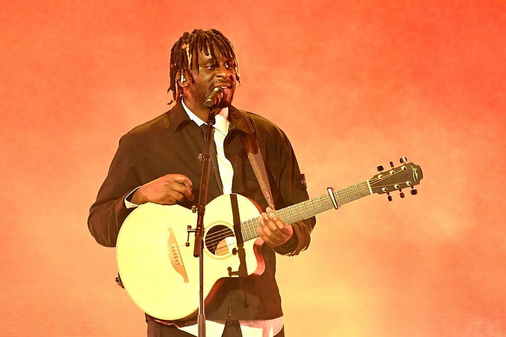 Myles Smith standing on stage with his guitar 