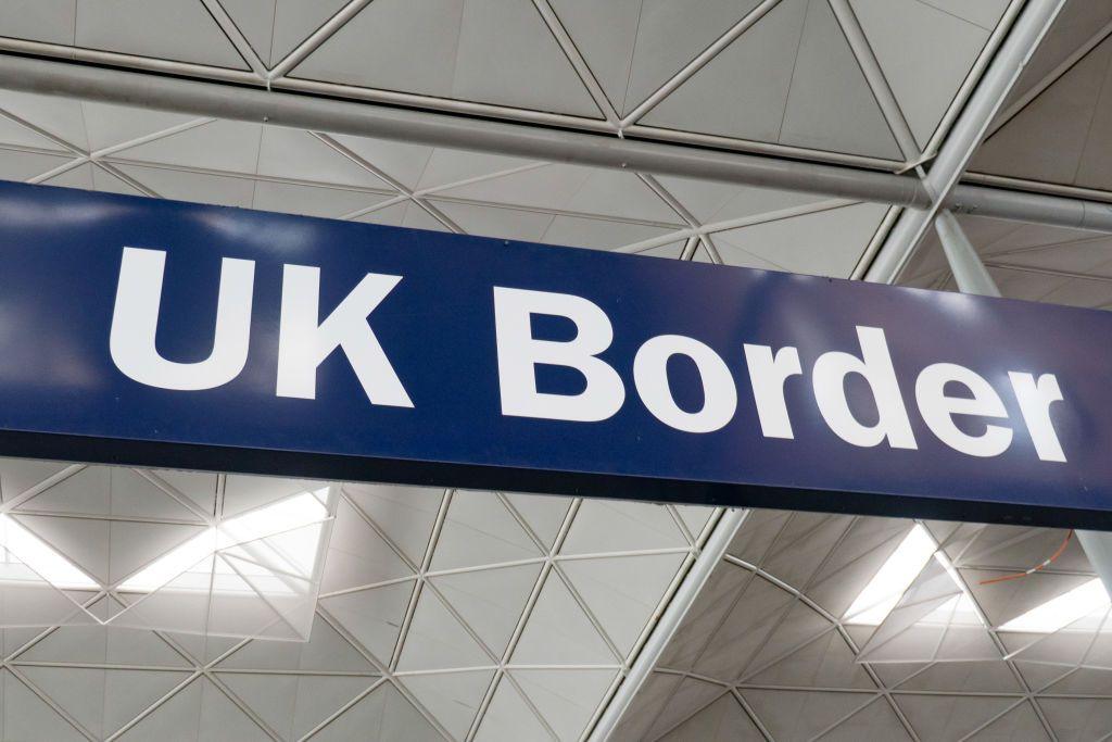 Close up of a large blue sign reading "UK border", which hangs from the ceiling