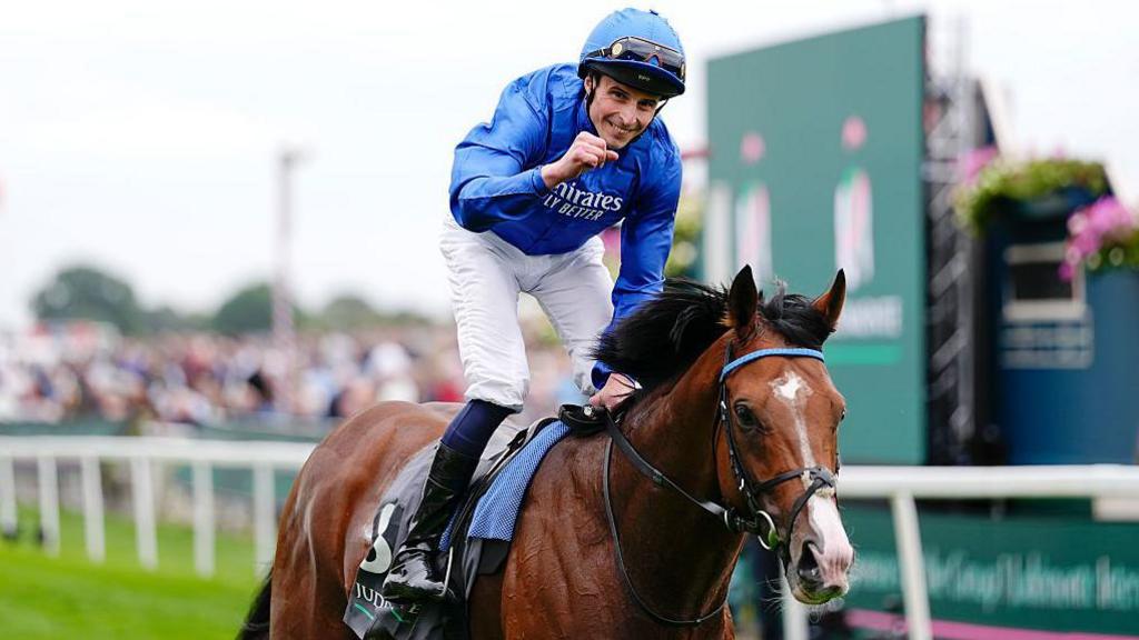 Jockey William Buick holds up his fist as he celebrates victory on Ombudsman