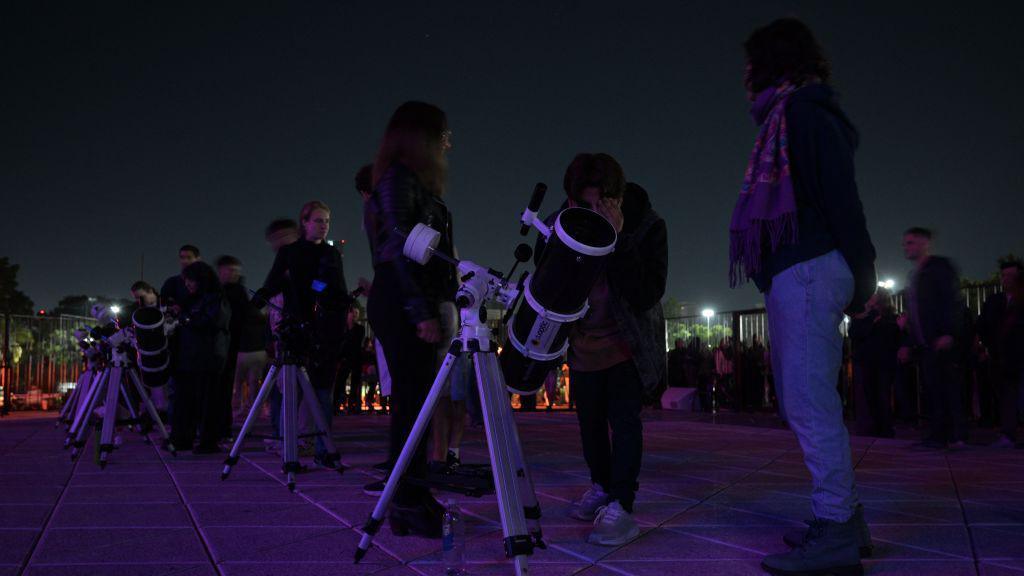 People looking through telescopes at Galileo Galilei Planetarium in Buenos Aires in Argentina.