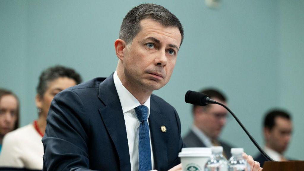 Pete Buttigieg sits in front of microphone