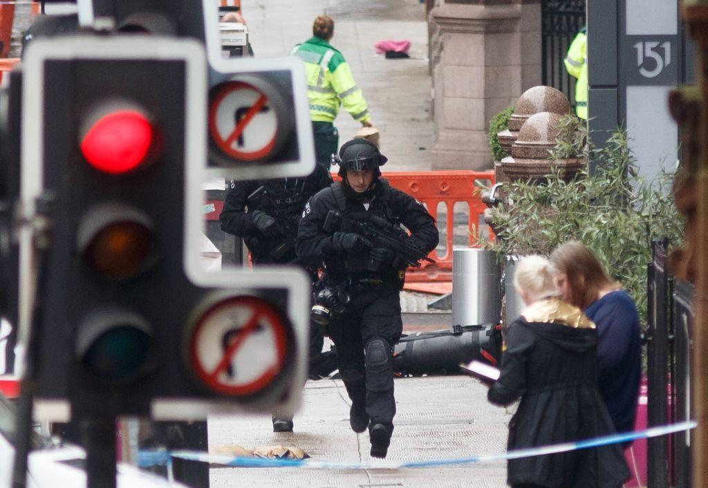 An armed police officer runs uphill in an area cordoned off outside the Park Inn hotel