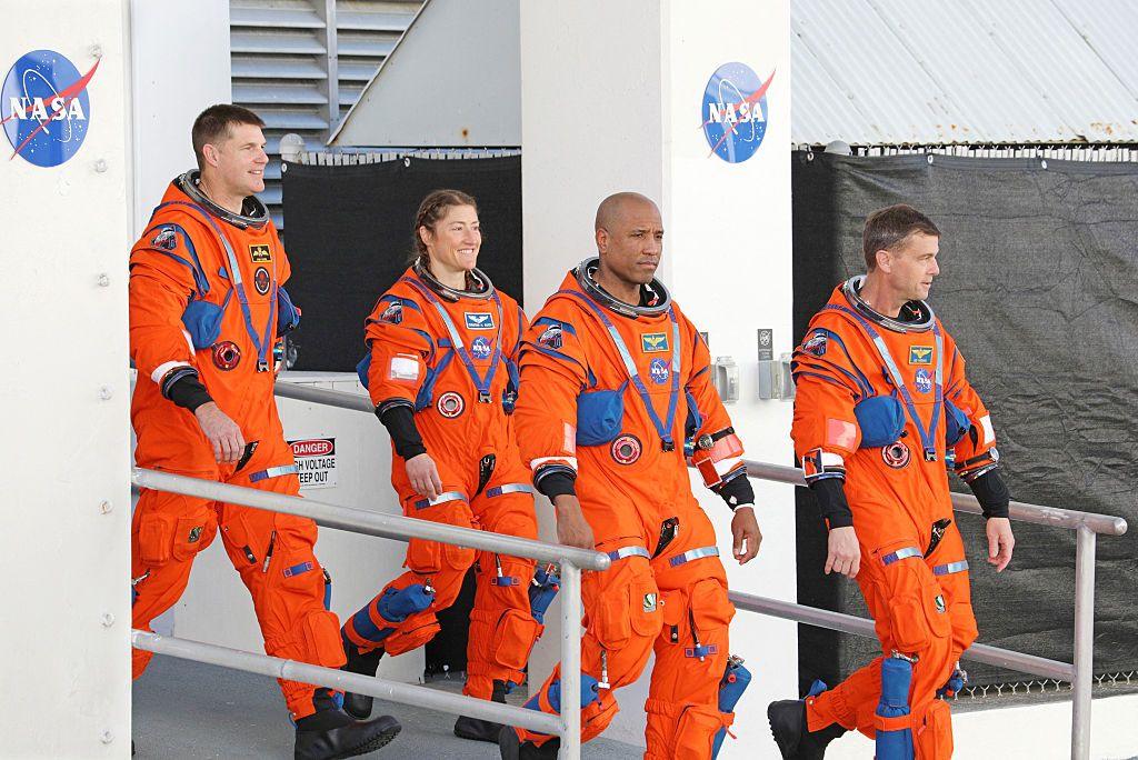 Nasa Artemis II mission astronauts (from left to right) Jeremy Hansen, Christina Koch, Victor Glover and Reid Wiseman in orange space suits without helmets walk down a ramp. 