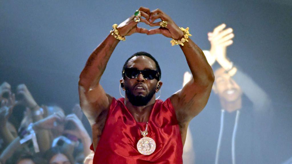 Sean 'Diddy' Combs, pictured at the 2023 MTV Awards, holds his arms above his head and makes a "heart" symbol with his hands.