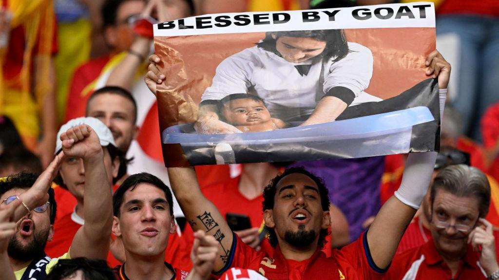Spain fans hold up a picture of Messi bathing Yamal as a baby